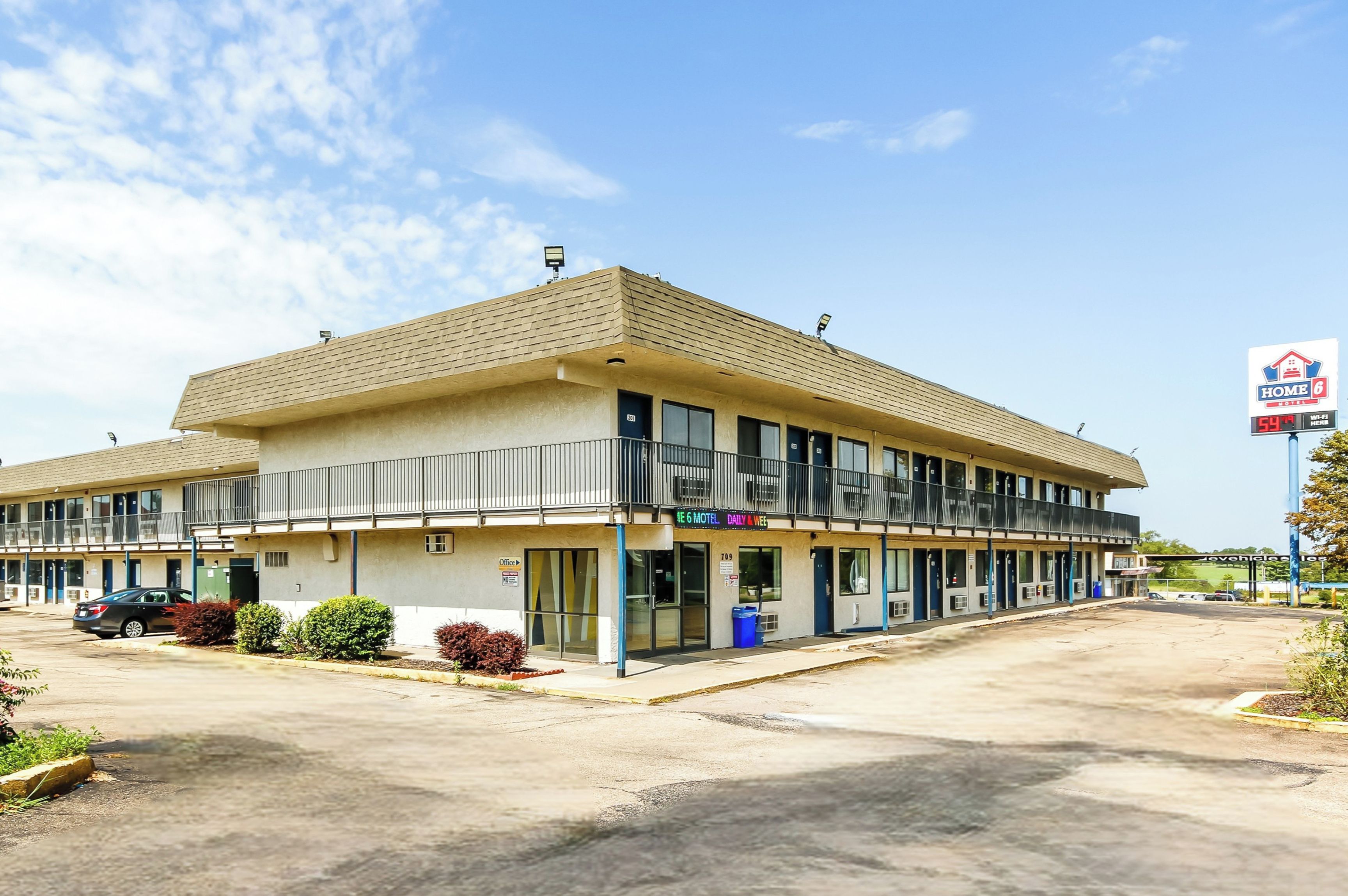 Un motel de dos pisos, con estacionamiento y un cartel que indica su nombre y servicios.