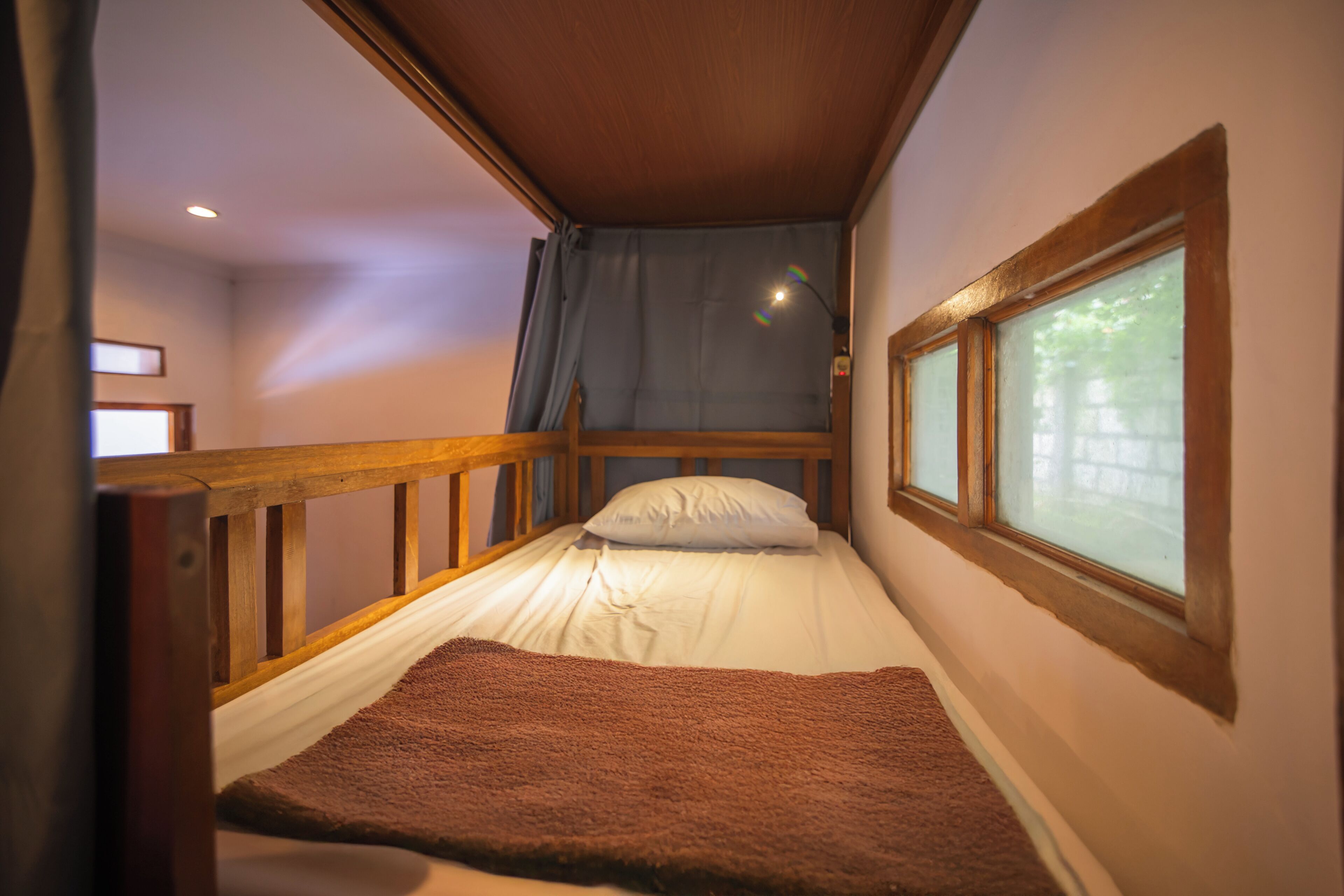 Une petite chambre accueillante, avec un lit simple, une fenêtre donnant sur un beau paysage et une rambarde en bois.