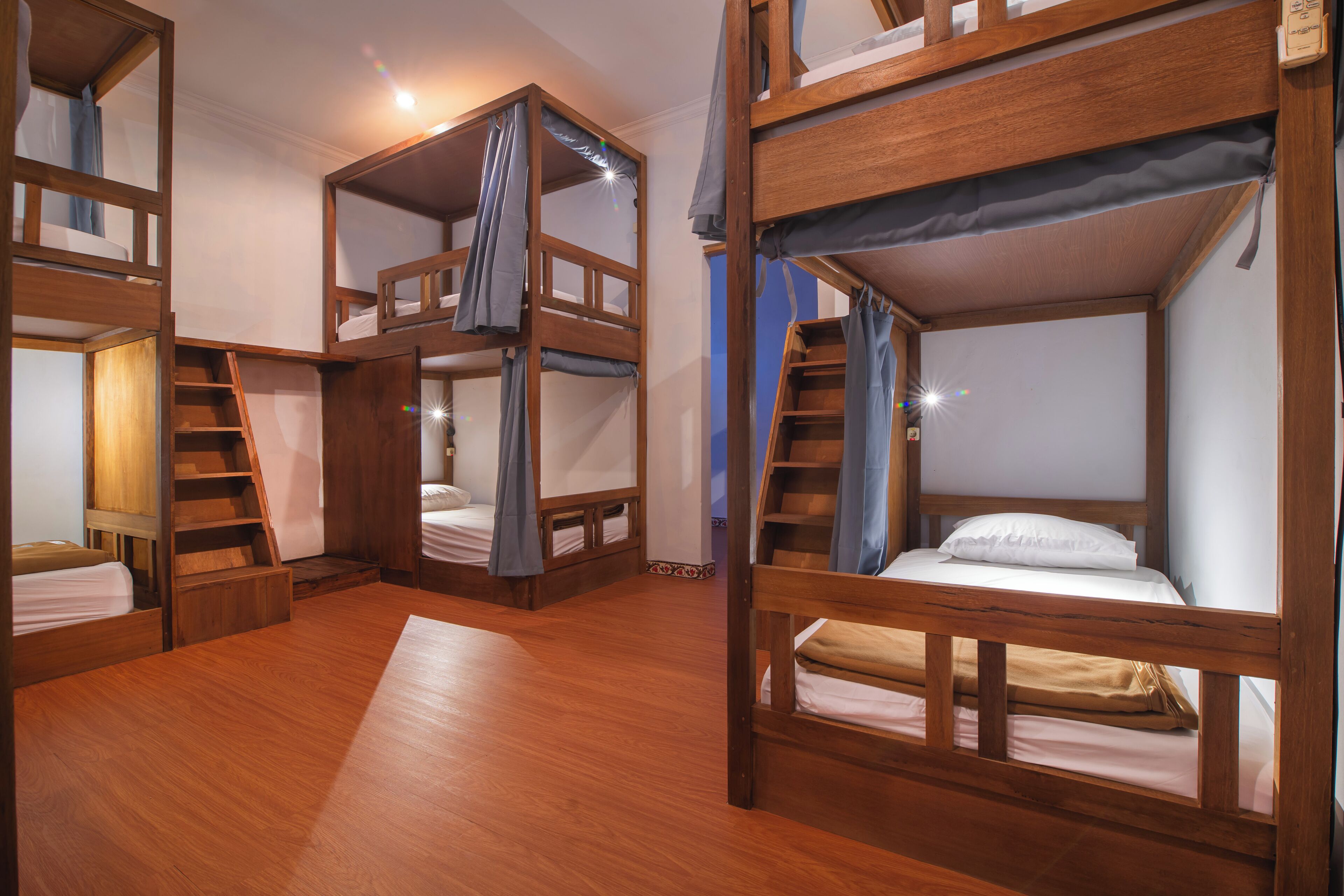 A room with bunk beds, wooden floors, and a staircase.