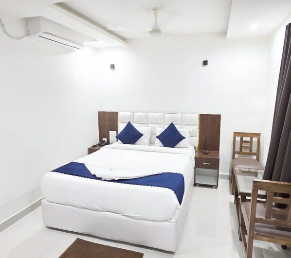 A modern hotel room with a large bed, bedside tables, a desk, and a chair. - Hotel Skyland (Warangal)