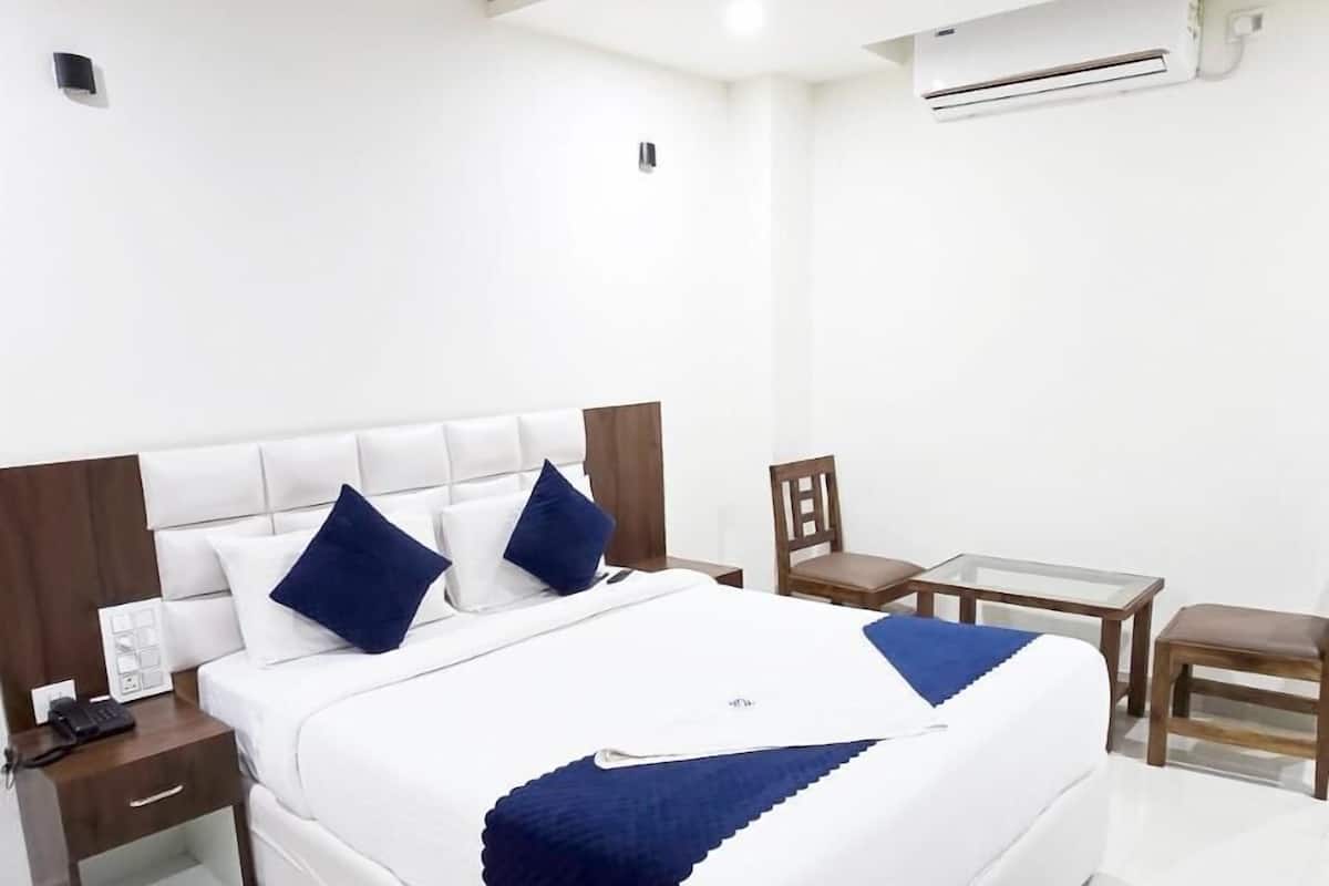 Une chambre d’hôtel moderne équipée d’un grand lit, de tables de chevet, d’un bureau et d’un appareil de climatisation.