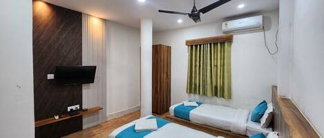 Una habitación de hotel con dos camas, televisión, aire acondicionado y ventilador de techo.