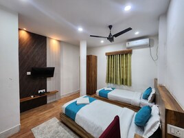 Una habitación de hotel con dos camas, televisión, aire acondicionado y ventilador de techo.