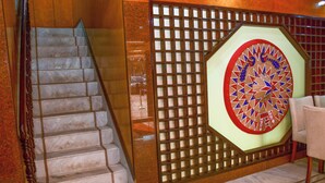 A staircase with a wooden handrail and a decorative wall panel with a geometric pattern.