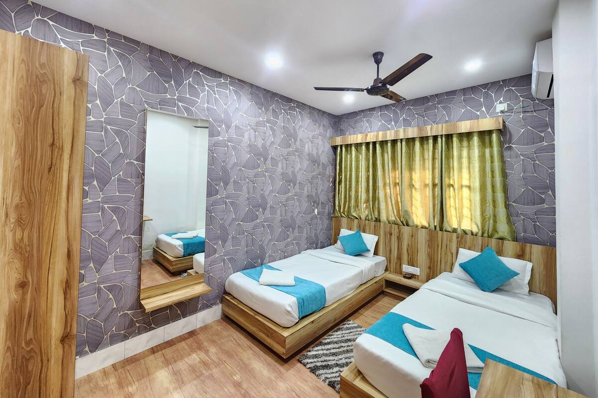 A bedroom with two single beds, a ceiling fan, and a window with curtains.