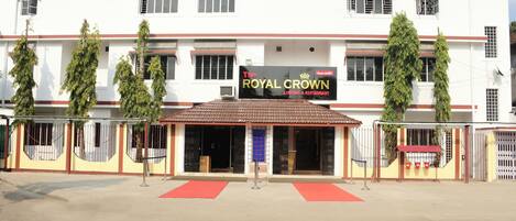 A hotel named "The Royal Crown" with a red awning, a gated entrance, and a tiled roof.