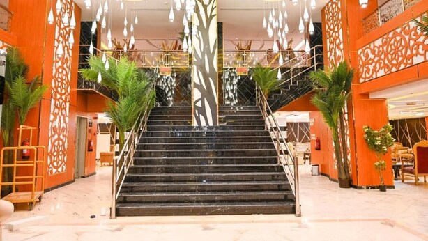 A hotel lobby with a central staircase, decorative panels, and hanging light fixtures. - Aseel Almisk Hotel (Makkah)