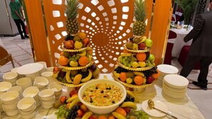 A buffet setup with fruit and vegetable platters, bowls of salad, and stacked plates. - Aseel Almisk Hotel (Makkah)