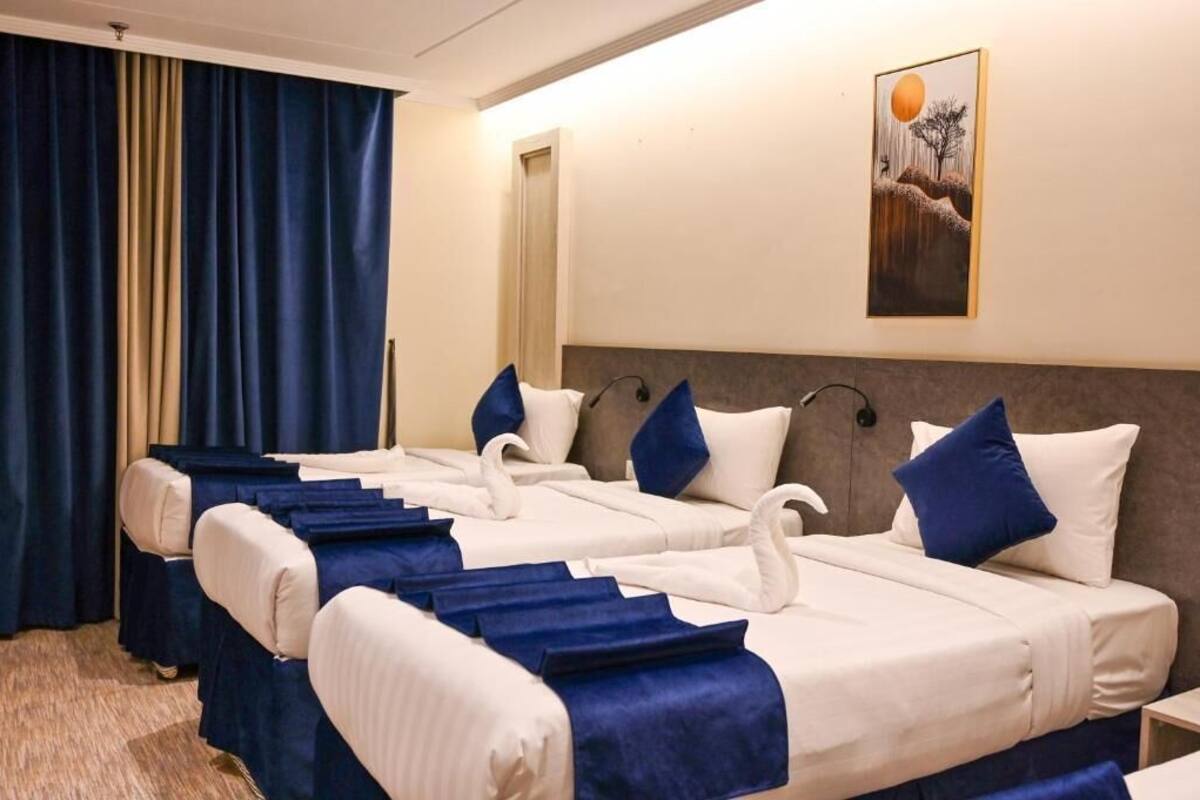 Hotellihuone, jossa on suuri sänky, pääty, taulu seinällä ja ikkuna, jossa on verhot.