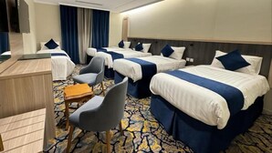 A hotel room with three beds, a desk, and a chair. - Aseel Almisk Hotel (Makkah)