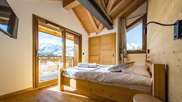 A wooden bedroom with a bed, a window, and a view of a snowy mountain. - Sylodges 202 - Spacious apartment for 10/12 people (LA TOUSSUIRE)