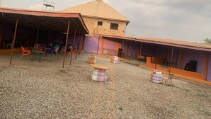 A building with a tiled roof and a covered outdoor seating area with tables and chairs. - The CEO hotel and suite  (Ibadan)