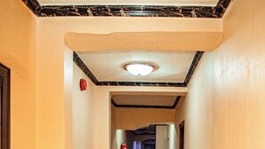A long, narrow hallway with wooden flooring and cream-colored walls. - The CEO hotel and suite  (Ibadan)
