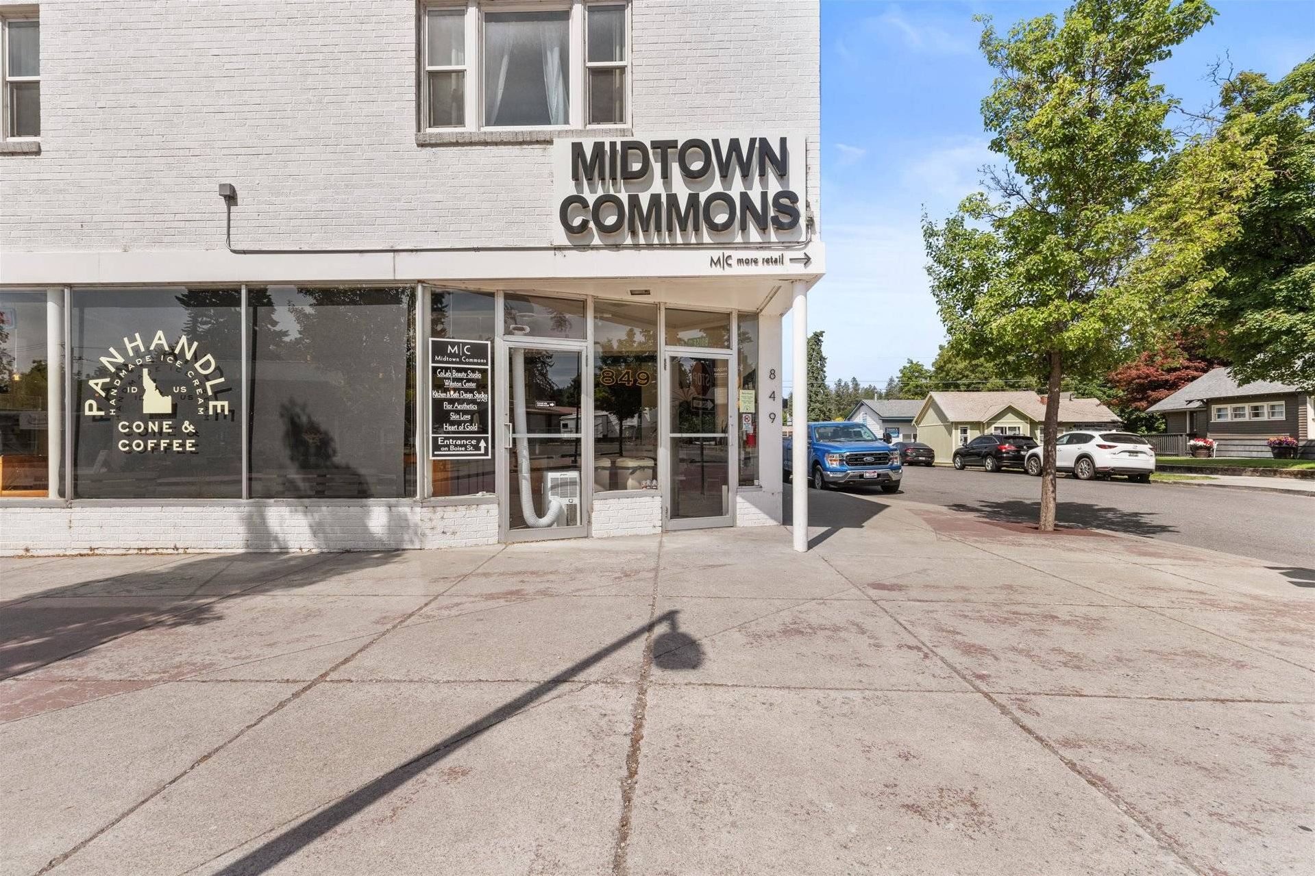 Un edificio con un letrero que dice "MIDTOWN COMMONS" y una tienda con un anuncio de "PANHANDLE ICE CREAM CONE & COFFEE".