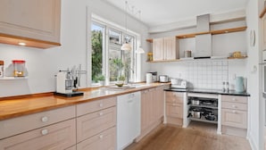 Eine moderne Küche mit Holzarbeitsplatten, weißen Schränken und einem großen Fenster, das für natürliches Licht sorgt.