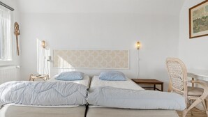 Ein Schlafzimmer mit einem Bett, zwei Nachttischen, einem Sessel und einer Wandleuchte.