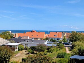 Zona residencial costera con casas, cielo despejado y el mar al fondo.