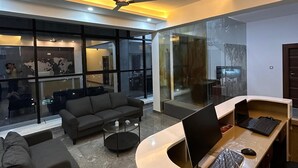 Ένας σύγχρονος χώρος καθιστικού με μια καμπυλωτή ρεσεψιόν, έναν καναπέ, ένα τραπεζάκι και έναν φορητό υπολογιστή πάνω στο γραφείο.