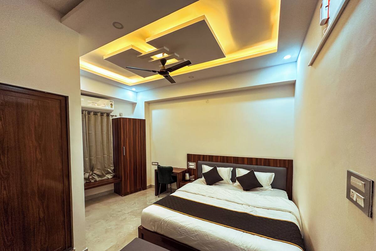 A modern bedroom with a large bed, a desk, and a wardrobe.
