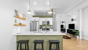 Une cuisine moderne dotée d’un îlot central, de tabourets de bar et d’un coin repas avec une table et des chaises.
