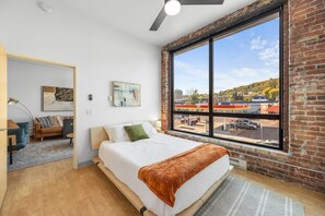Une chambre avec une grande fenêtre, un lit, un bureau et une vue sur une station-service.