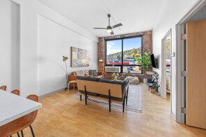 Un salon moderne comprenant un canapé, une table à manger et une grande fenêtre donnant sur l’extérieur.