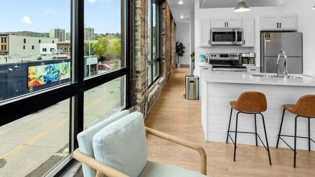 A modern kitchen with white cabinets, a central island, and bar stools. - Craft District Apt w/ Gym & Coffee Shop 207 (Duluth)