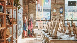 A spacious art studio with wooden floors, shelves with art supplies, and easels set up for painting.
