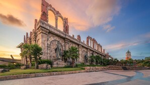 A large stone structure with arches and columns, surrounded by a paved area and palm trees. - KIEN HOTEL (Phu Quoc)