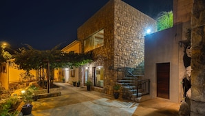 Un edificio de piedra con escaleras, plantas en macetas y un espacio exterior bien iluminado.