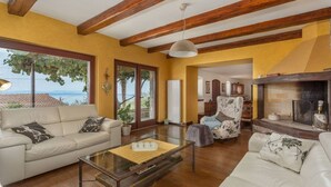 Una sala de estar con sofá, sillón y mesa de centro, chimenea y vistas al exterior.
