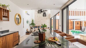 Une cuisine moderne dotée d’un îlot central, de meubles en bois et d’une grande fenêtre donnant sur une piscine.