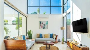 Amplia sala de estar con un ventanal grande, un conjunto de sofá, una mesa de centro y un televisor de pantalla plana.