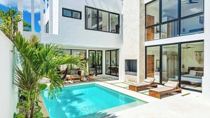 Una casa moderna con piscina, ventanas amplias y zonas de estar al aire libre.