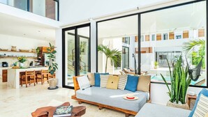 Una sala de estar moderna con sofá, mesa de centro y vistas a una piscina y zona exterior.
