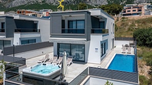 A modern hotel with a rooftop pool, outdoor seating, and a hot tub.