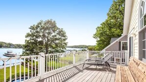 Une terrasse en bois avec une balustrade blanche, un banc et une table.
