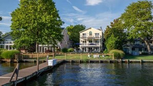 Une propriété située au bord de l’eau, dotée d’un quai, d’un grand arbre et d’une maison à plusieurs étages avec un balcon.