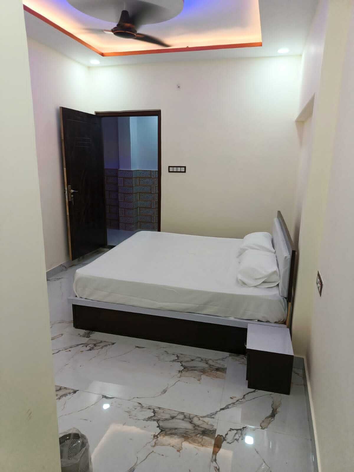 A bedroom with a bed, a ceiling fan, and a door leading to a balcony.