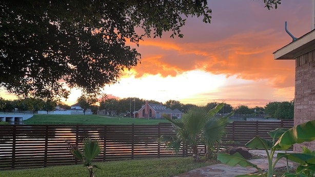 A stone pathway leading to a grassy area with a wooden fence and a brick building. - Charming Pond Villa 3-bedroom 2 Bath house DFW (Grand Prairie)