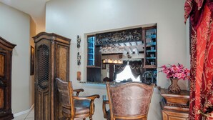 A dining area with a wooden table and chairs, a cabinet, and a decorative shelf with glassware. - Charming Pond Villa 3-bedroom 2 Bath house DFW (Grand Prairie)
