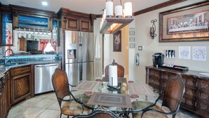 A modern kitchen with stainless steel appliances, a glass dining table, and wooden cabinetry. - Charming Pond Villa 3-bedroom 2 Bath house DFW (Grand Prairie)