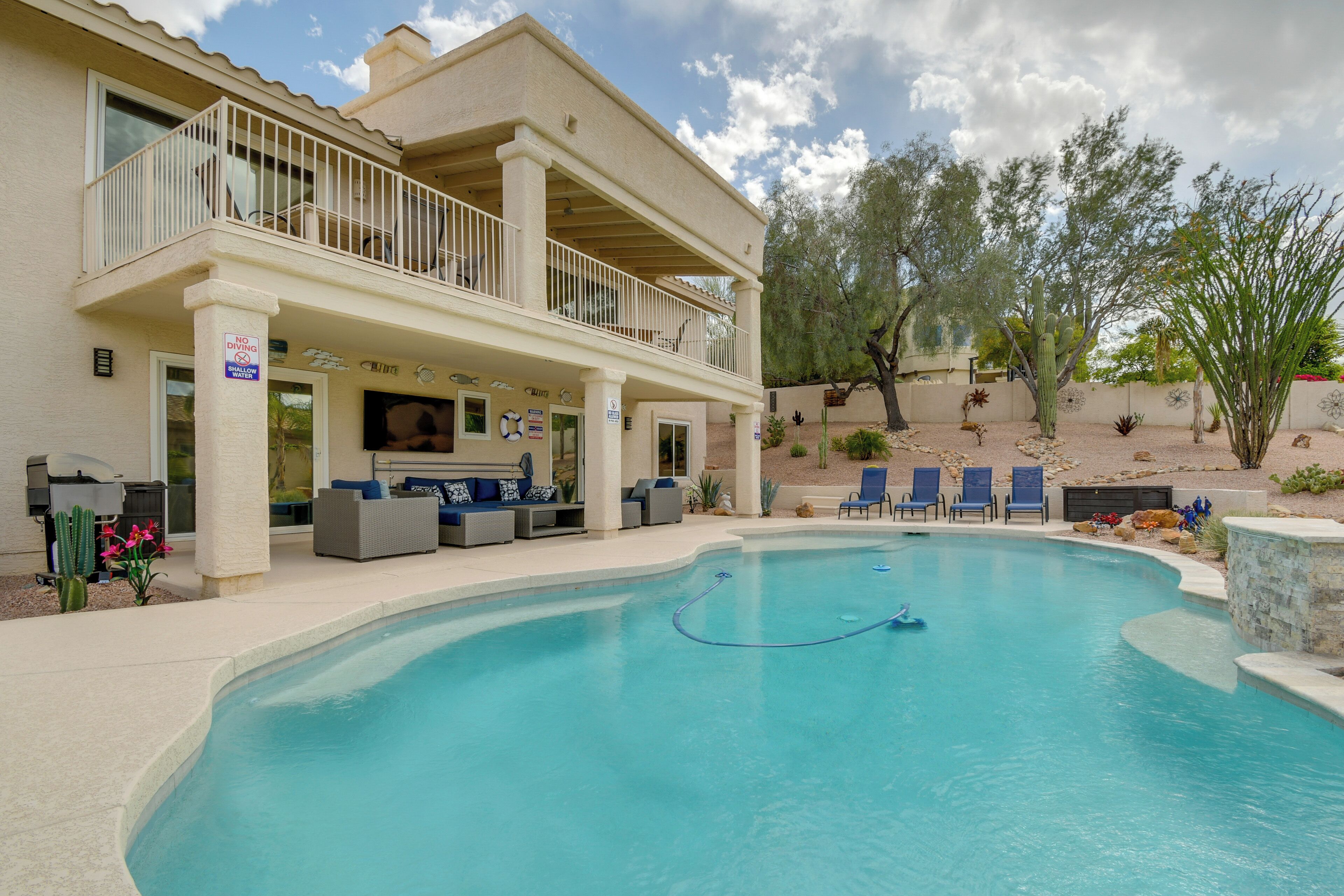 A pool area with a covered seating area, lounge chairs, and a cactus garden.