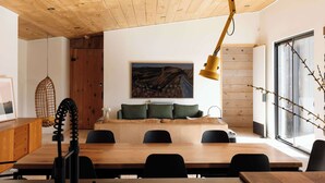 Ein moderner Essbereich mit Holzboden, einem großen Gemälde an der Wand und Blick ins Freie durch ein großes Fenster.