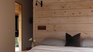 Ein Schlafzimmer mit einem hölzernen Kopfende, einem Nachttisch mit Blumen und einem Bett mit zwei Kissen.