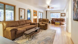 A spacious living room with a brown leather sofa, a wooden coffee table, and a ceiling fan. - Walk to Dining! Peaceful Arnold Cabin w/ Deck (Arnold)