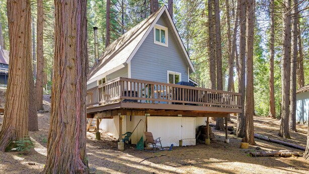 A cabin with a deck, surrounded by tall trees. - Hike, Ski & Sip: Arnold Cabin 4 Mi to State Park! (Arnold)