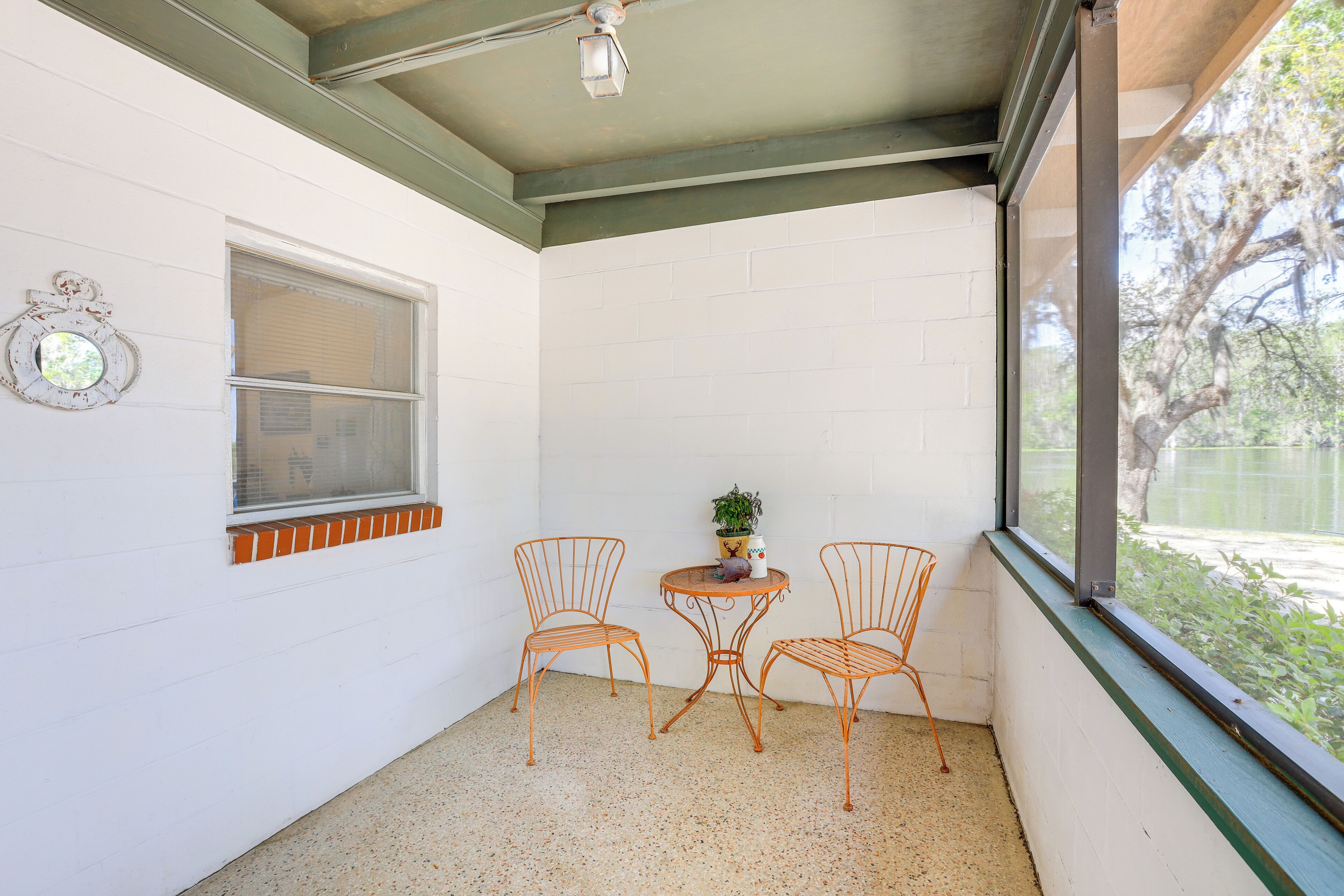 Une petite pièce aux murs blancs, avec une fenêtre, une table et deux chaises, et un ventilateur de plafond.