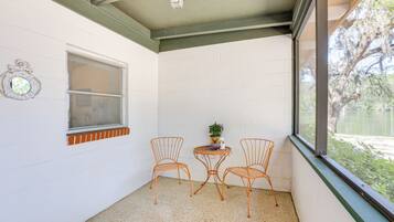 Une petite pièce aux murs blancs, avec une fenêtre, une table et deux chaises, et un ventilateur de plafond.