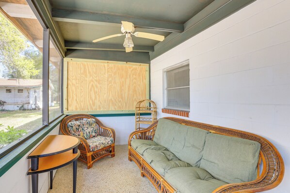 Une pièce dotée d’un ventilateur de plafond, d’un canapé en osier, de deux fauteuils en osier et d’une petite table.